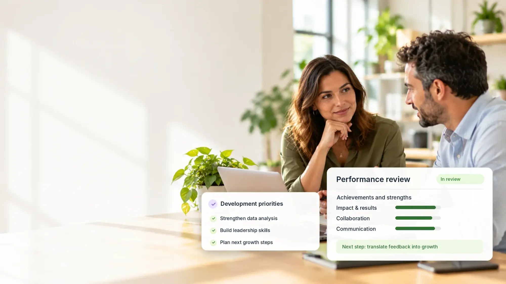 Employee and manager in conversation at a desk, with illustrative cards of a performance review and development priorities (not a product screenshot)